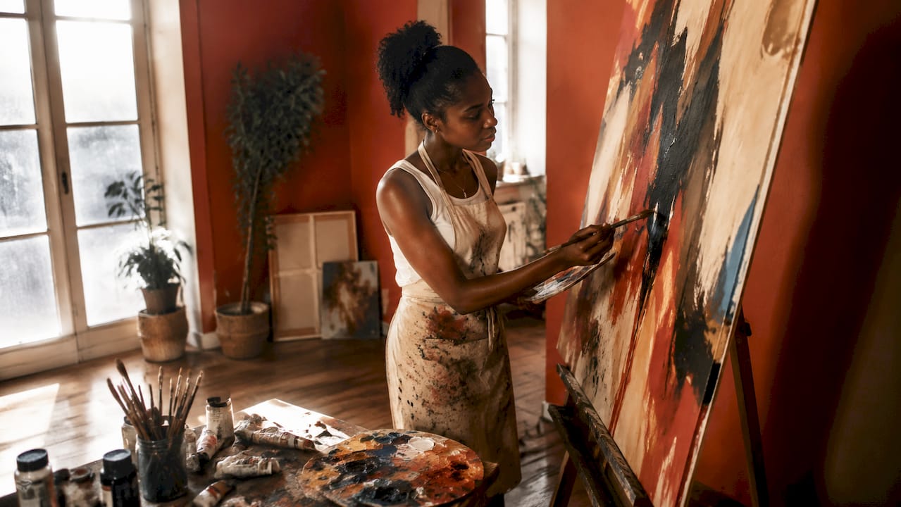 Black female artist painting in art studio
